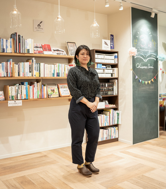 【画像】本棚の前に立つ上野智美さん