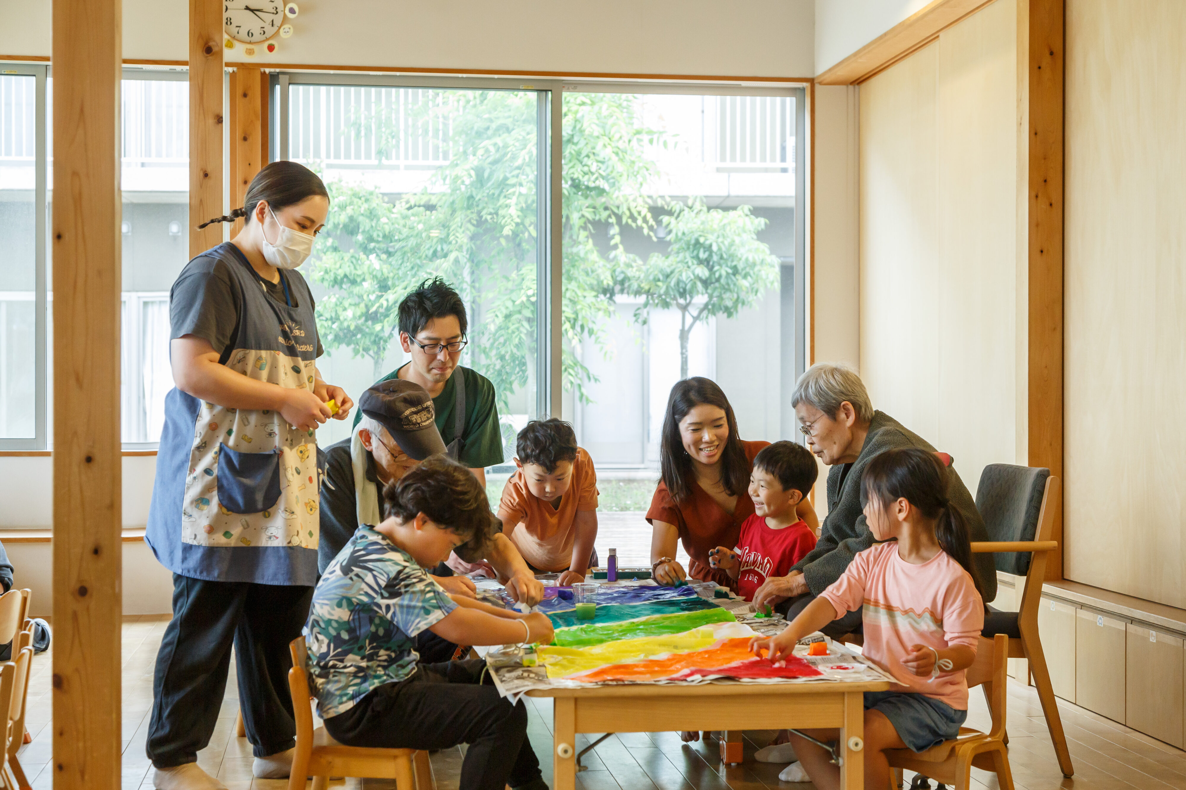 【写真】ローテーブルの机のまわりを、子供から高齢者まで幅広い層が囲んで談笑している