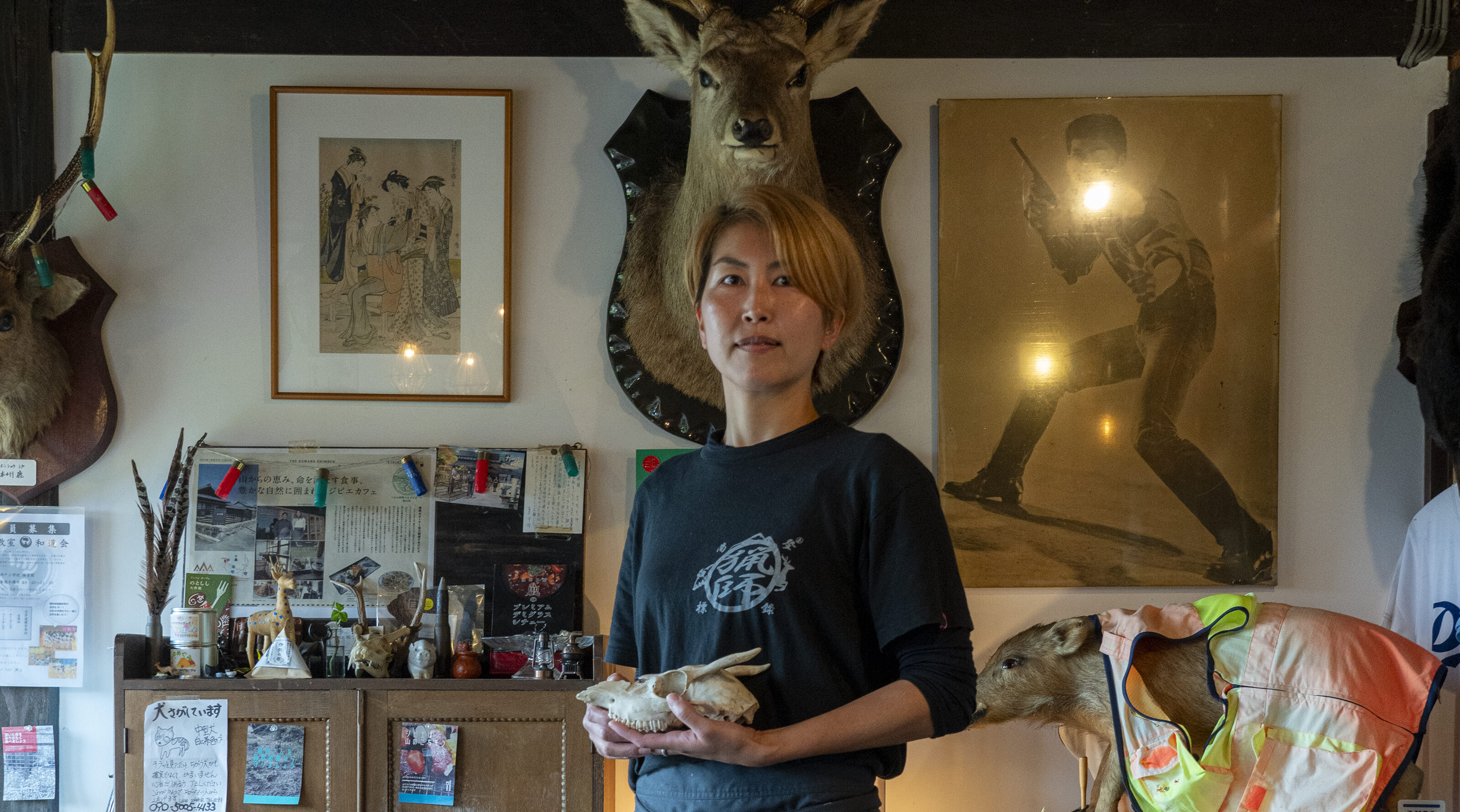 【写真】自身が経営するカフェ内に立つひおきさん。手には子鹿の骨を持っている。