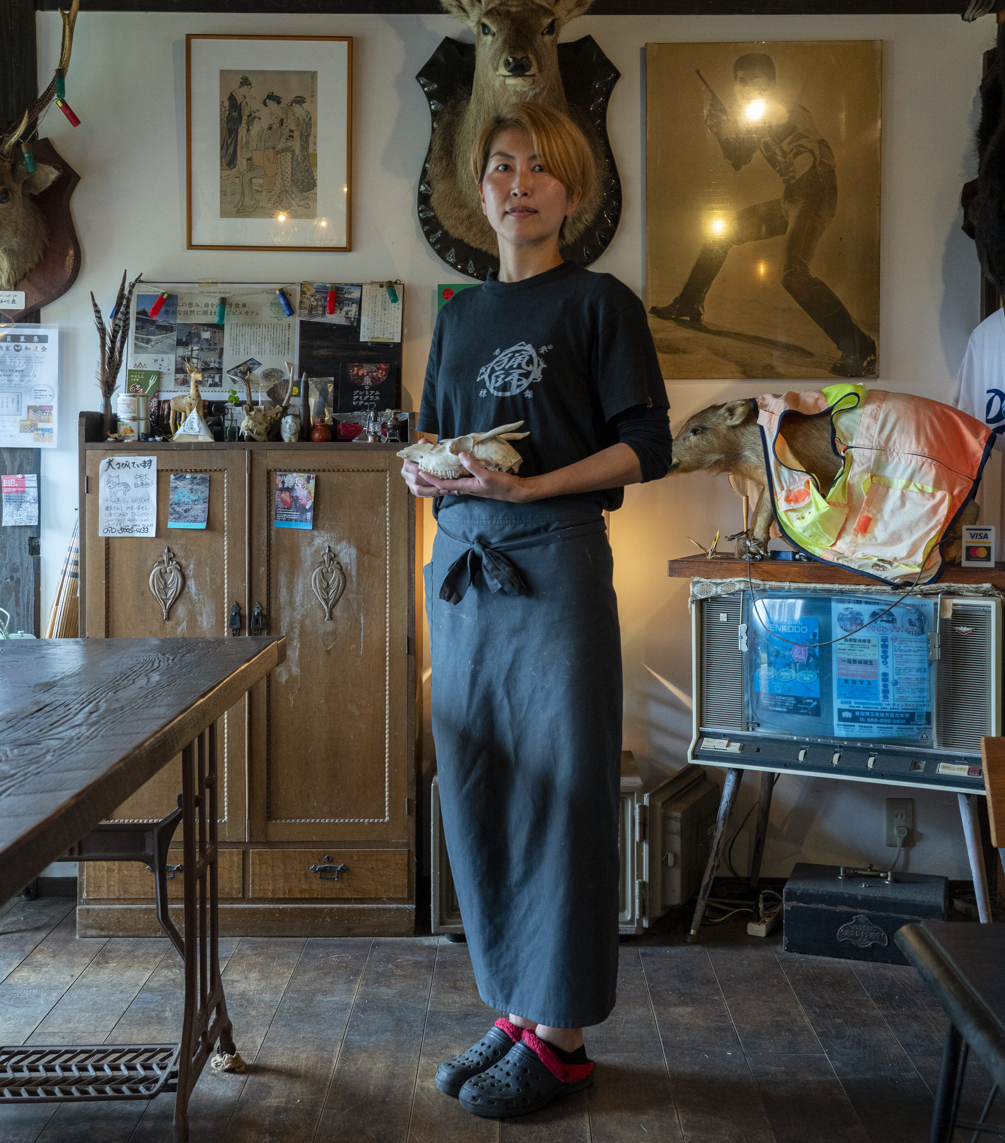 【写真】自身が経営するカフェ内に立つひおきさん。手には子鹿の骨を持っている。