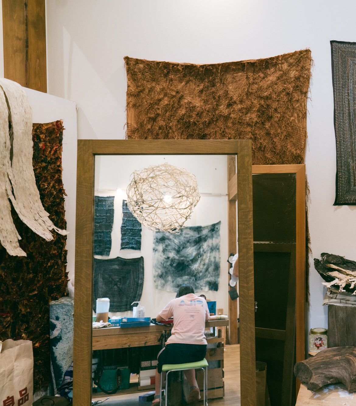 【写真】壁に大きな布が貼られている。その前に置いてあるか鍵に、作業をしている人の後ろ姿が映っている