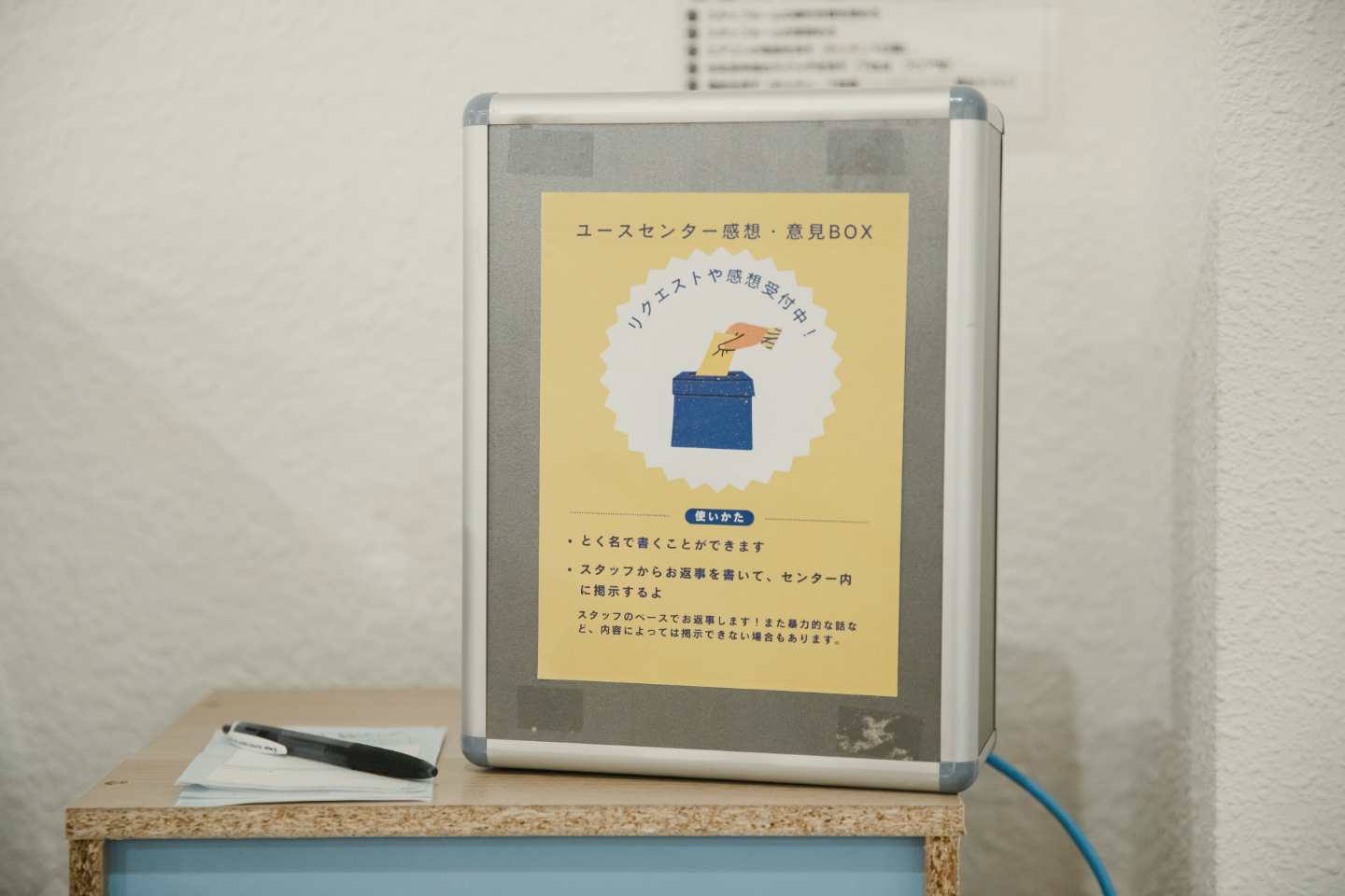 【写真】リクエストや感想受付中!の言葉が記された箱。同じ机の上にペンと用紙
