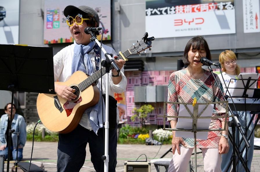 【写真】ギターを演奏するしんざわさん、マイクに向かって歌うみちこさん