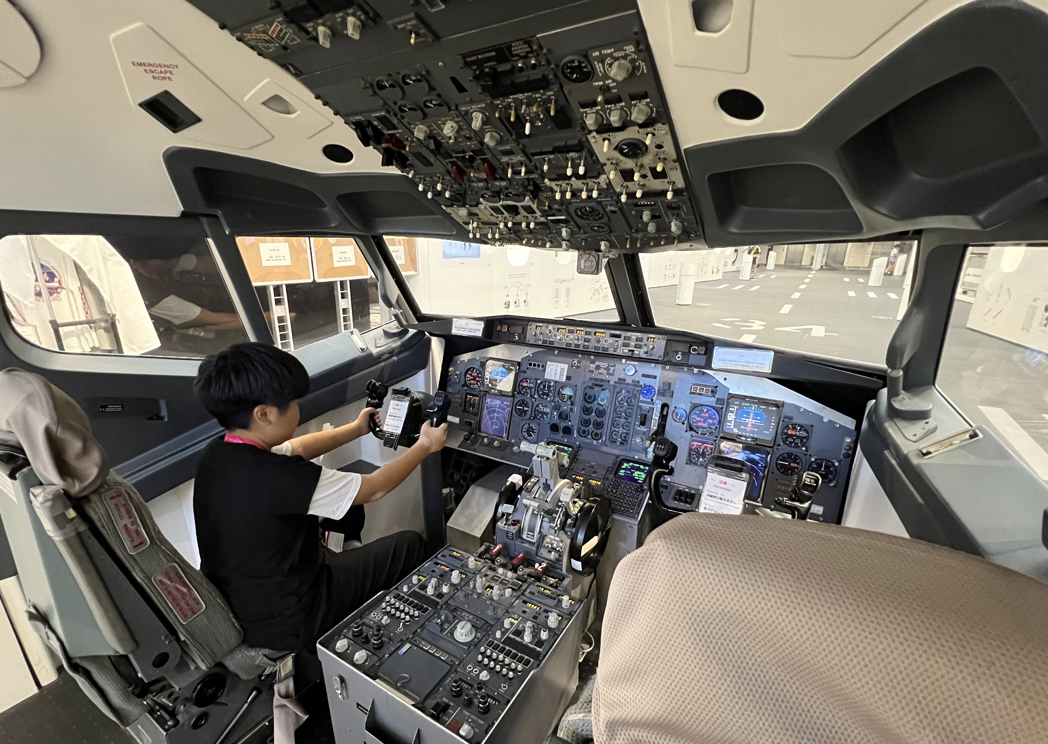 【写真】飛行機のコックピットに座ってレバーに手を触れている子ども