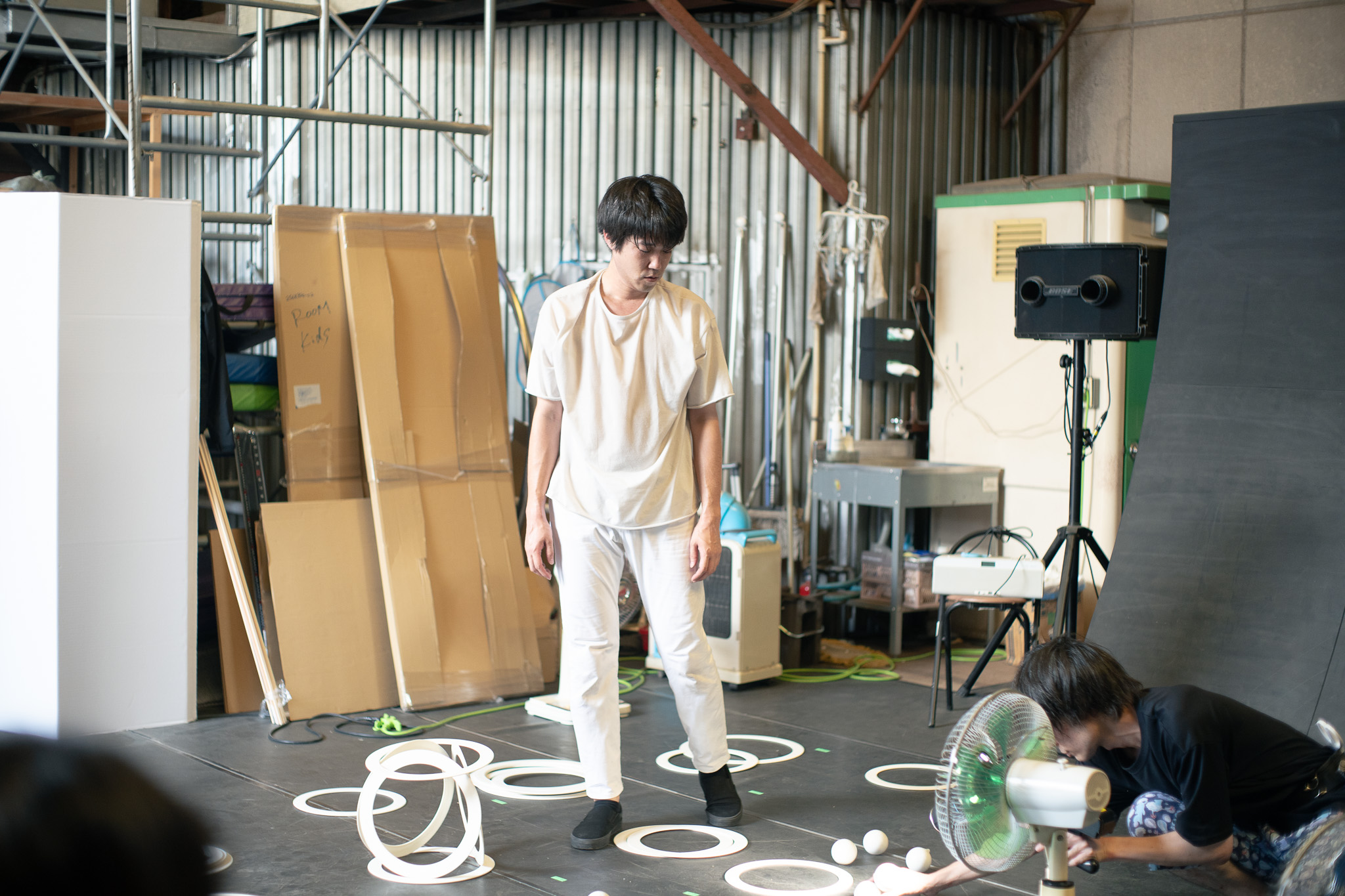 【写真】作品制作中と思われる風景。倉庫のような空間で、床にジャグリングの道具などが散らばっている