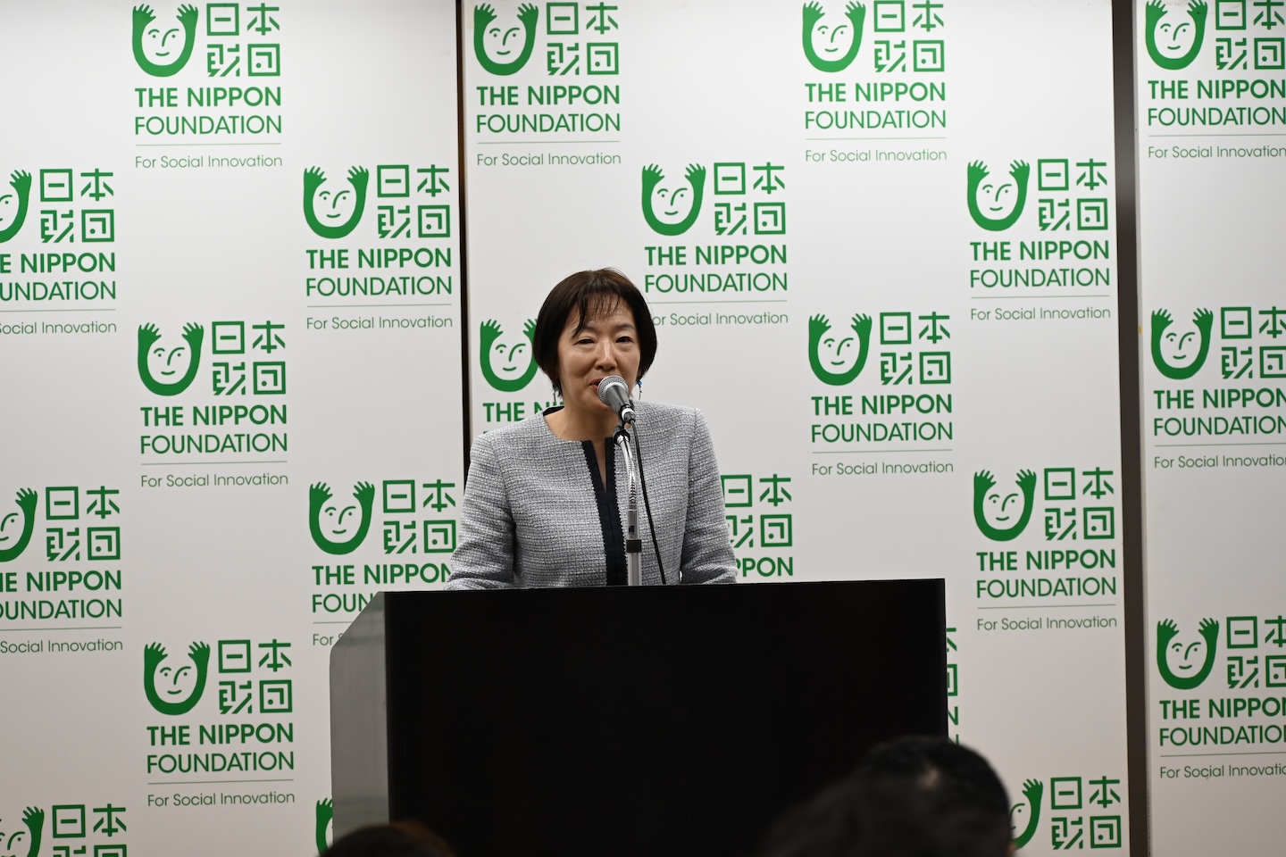演台でマイクを前に話している様子の写真