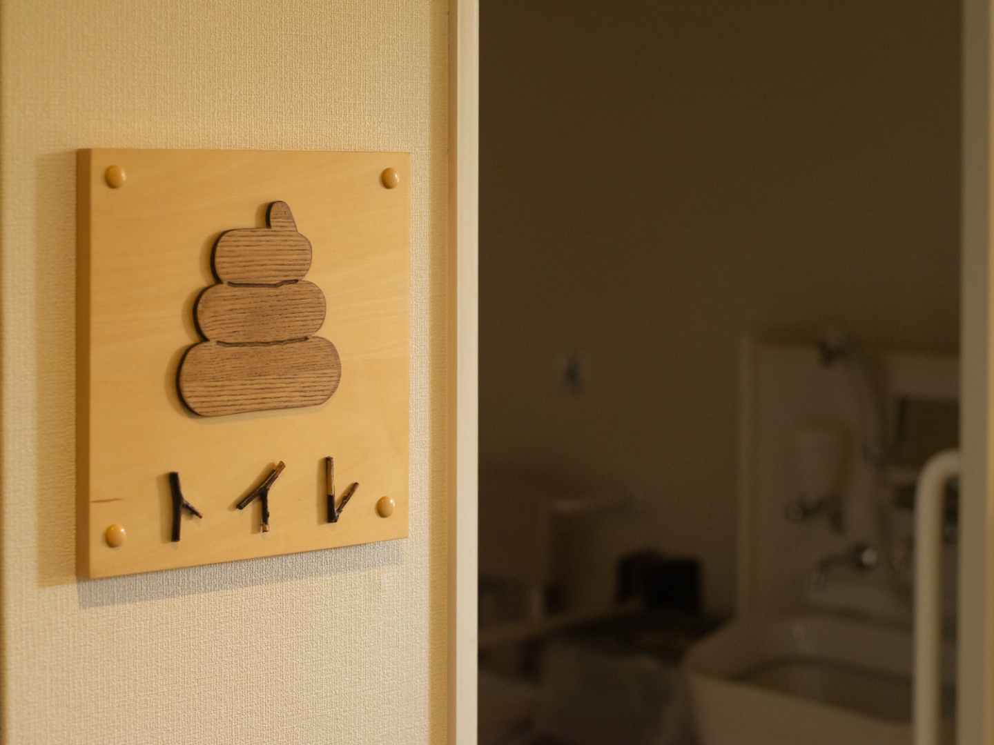【写真】うんちの形をしたイラストと、トイレの文字が浮き上がるルームプレート