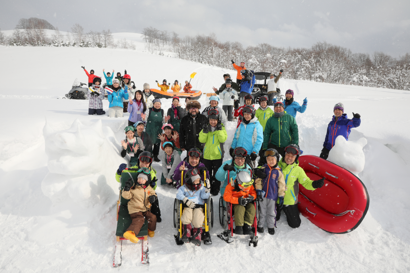 【写真】雪の中で親子がアクティビティに参加している様子。車椅子のスキーに乗っている子どももいる