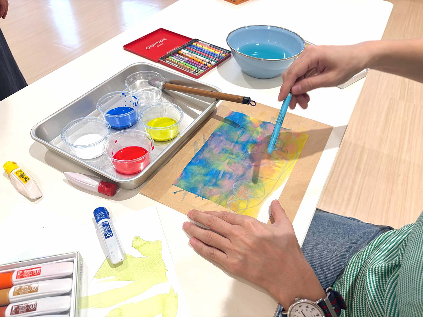 水絵の具を使って画用紙に色を乗せている様子の写真