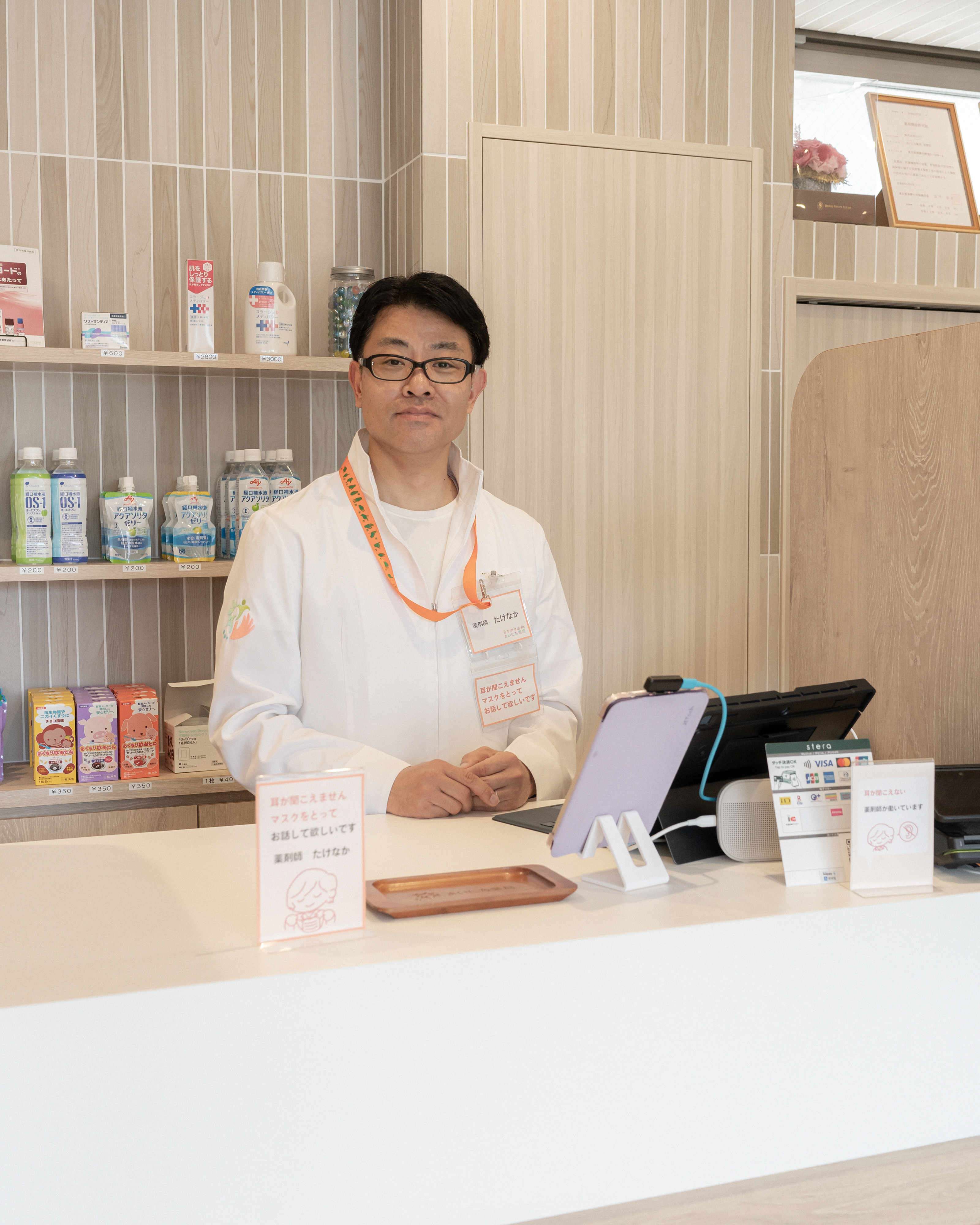 【写真】カウンターの前、黒い眼鏡をかけ、白いシャツを着てこちらをみるたけなかさん