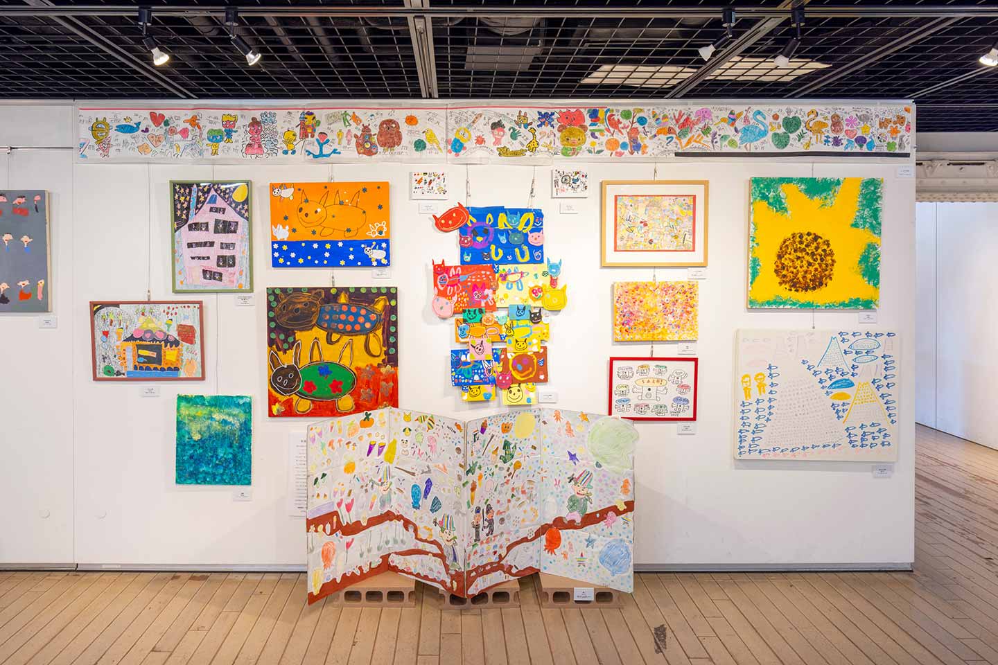 多種多様でカラフルな平面作品が壁に飾られた会場の様子。