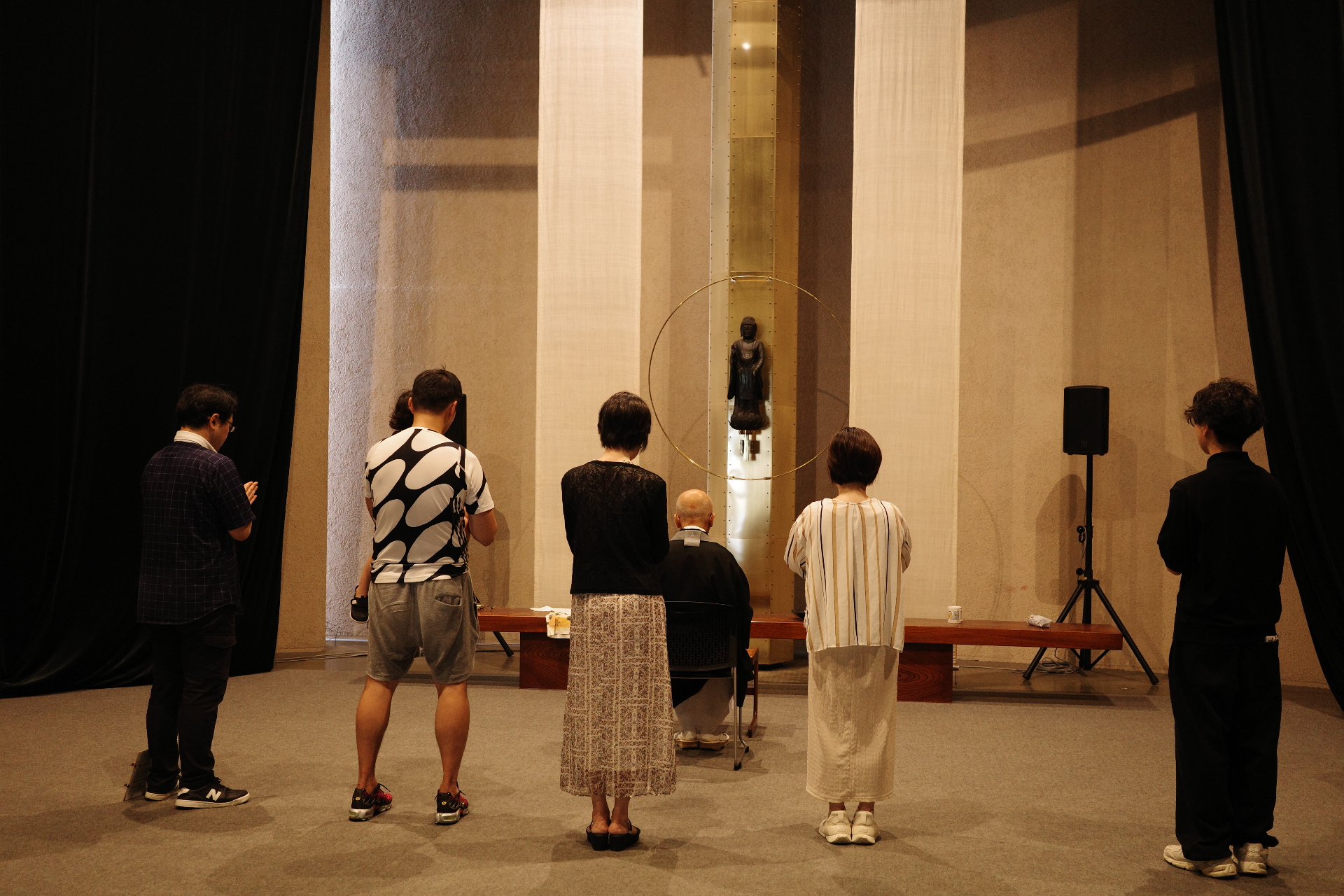 【写真】仏像と、その手前に並ぶ物に向けて、手を合わせる人びと