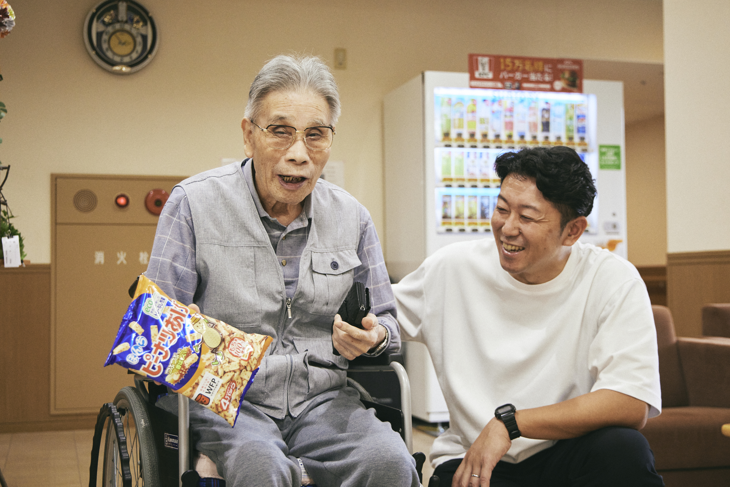 【写真】みさとひるずで過ごす利用者さん。車椅子を利用しながらお菓子を買いに行ったり、リビングでのびのび過ごしたりしている