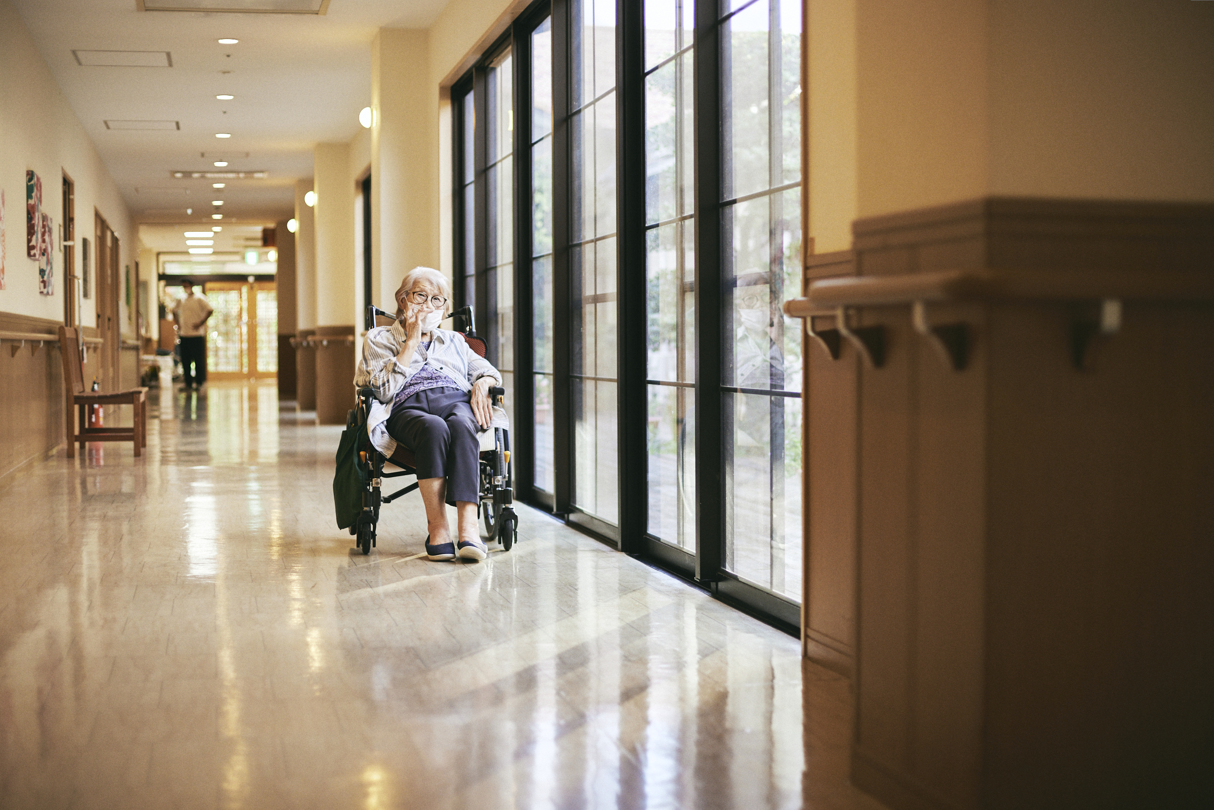 【写真】廊下、陽の光に当たっている入居者さん