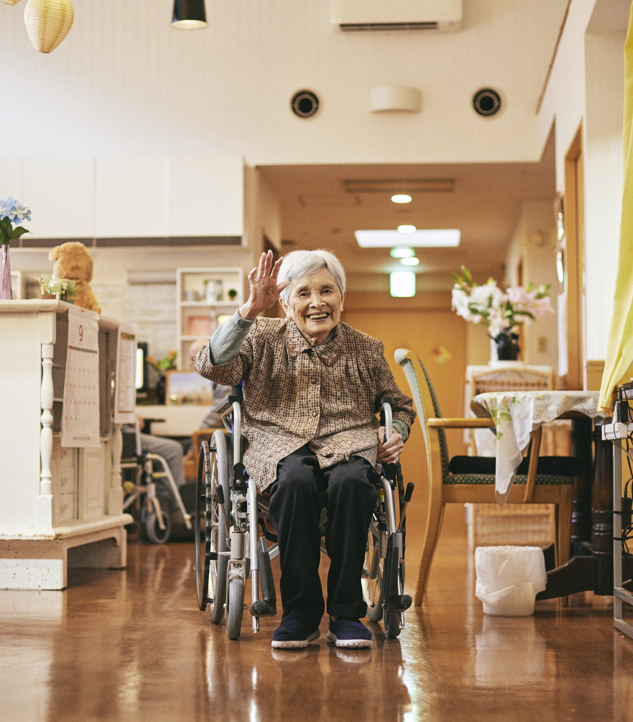 【写真】みさとひるずで過ごす利用者さん。車椅子を利用しながらお菓子を買いに行ったり、リビングでのびのび過ごしたりしている