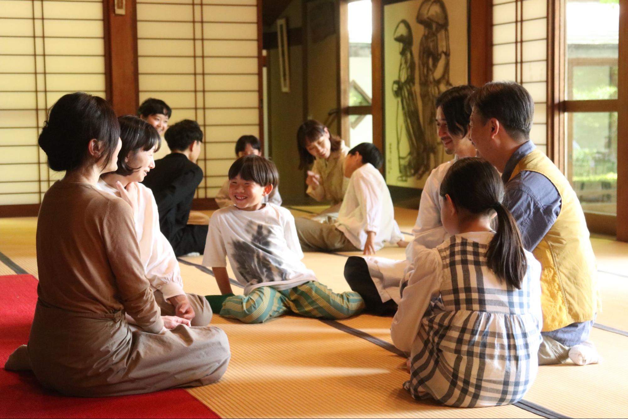 【画像】畳の敷き詰められた座敷で、いくつかの輪になって笑顔で話す子どもと大人