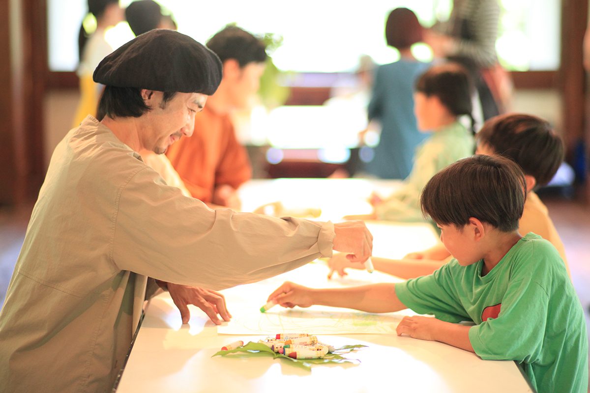【写真】テーブルの上でクレヨンを走らせる複数の親子