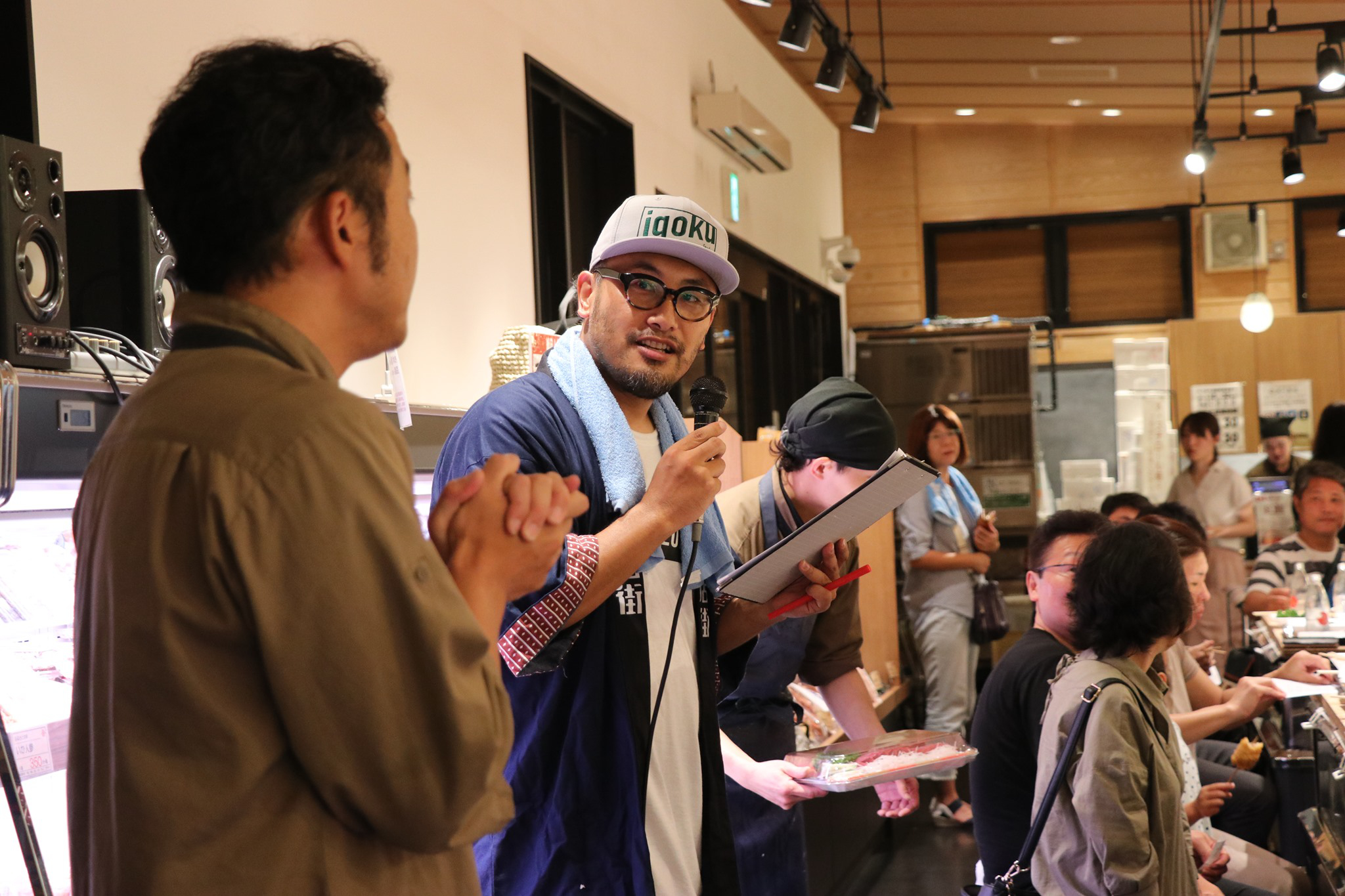 【写真】店内でマイクを握り話す小松さん