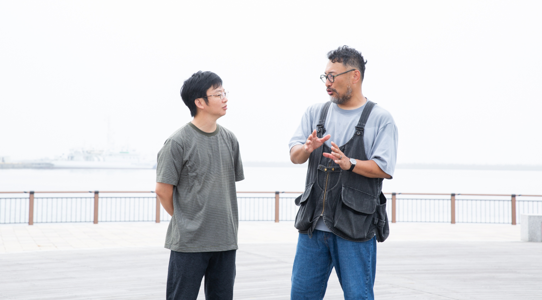 【写真】海をバックに、朝靄の中を向かい合って語りあう青山さんと小松さん