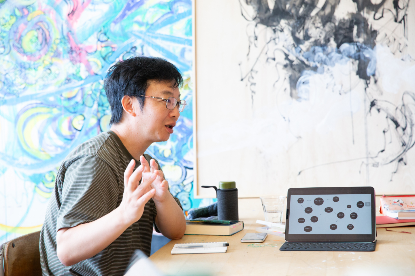 【写真】タブレットをみなに見せた状態で、手振りを交えて話す青山さんの横顔