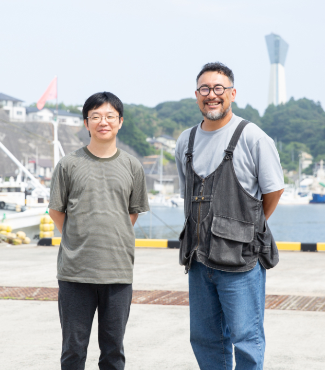 【写真】漁港をバックに笑顔でこちらを向く青山さんと小松さん