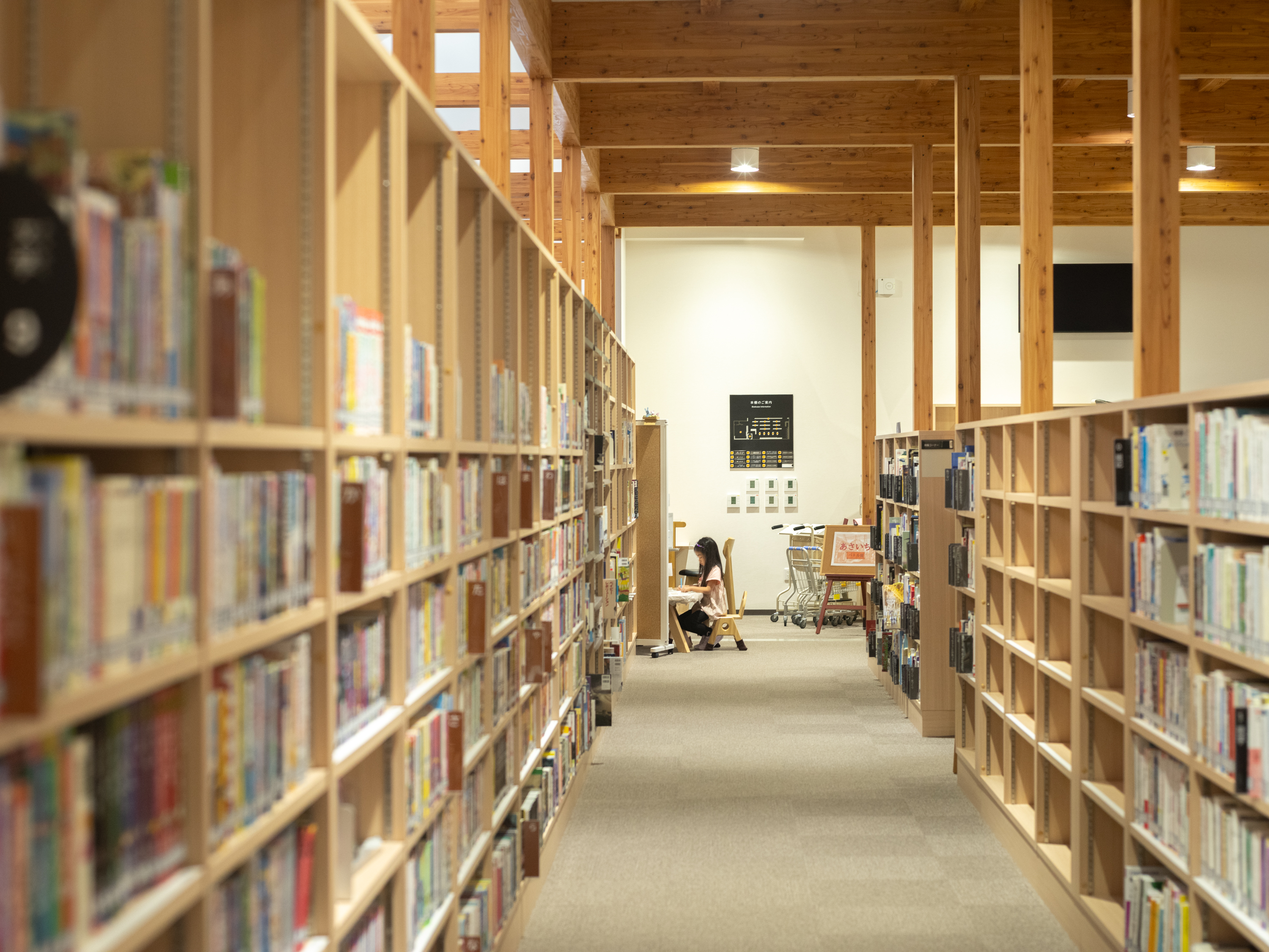 【写真】本棚に囲まれた場所で椅子に座って本を読む小学生