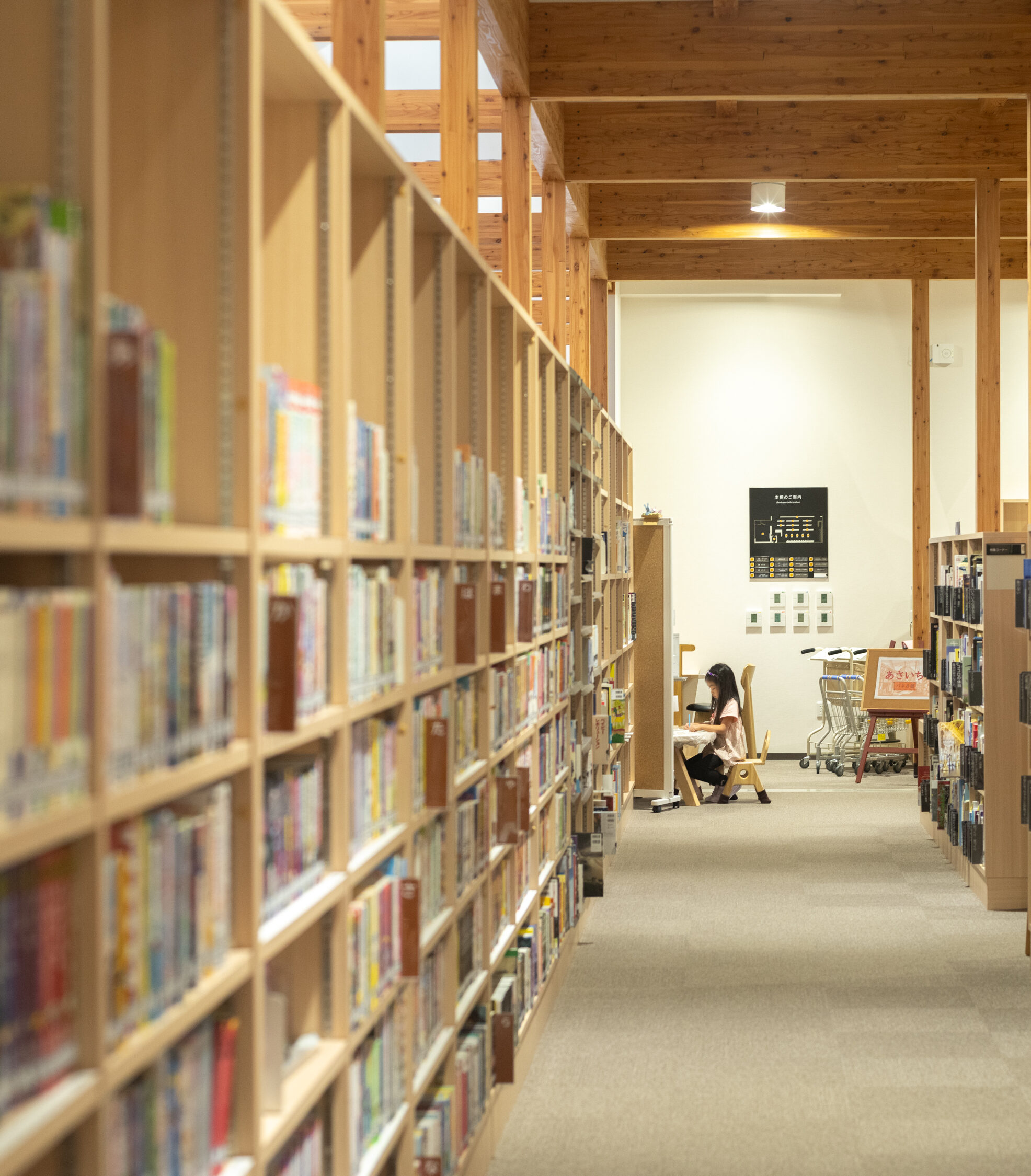 【写真】本棚に囲まれた場所で椅子に座って本を読む小学生