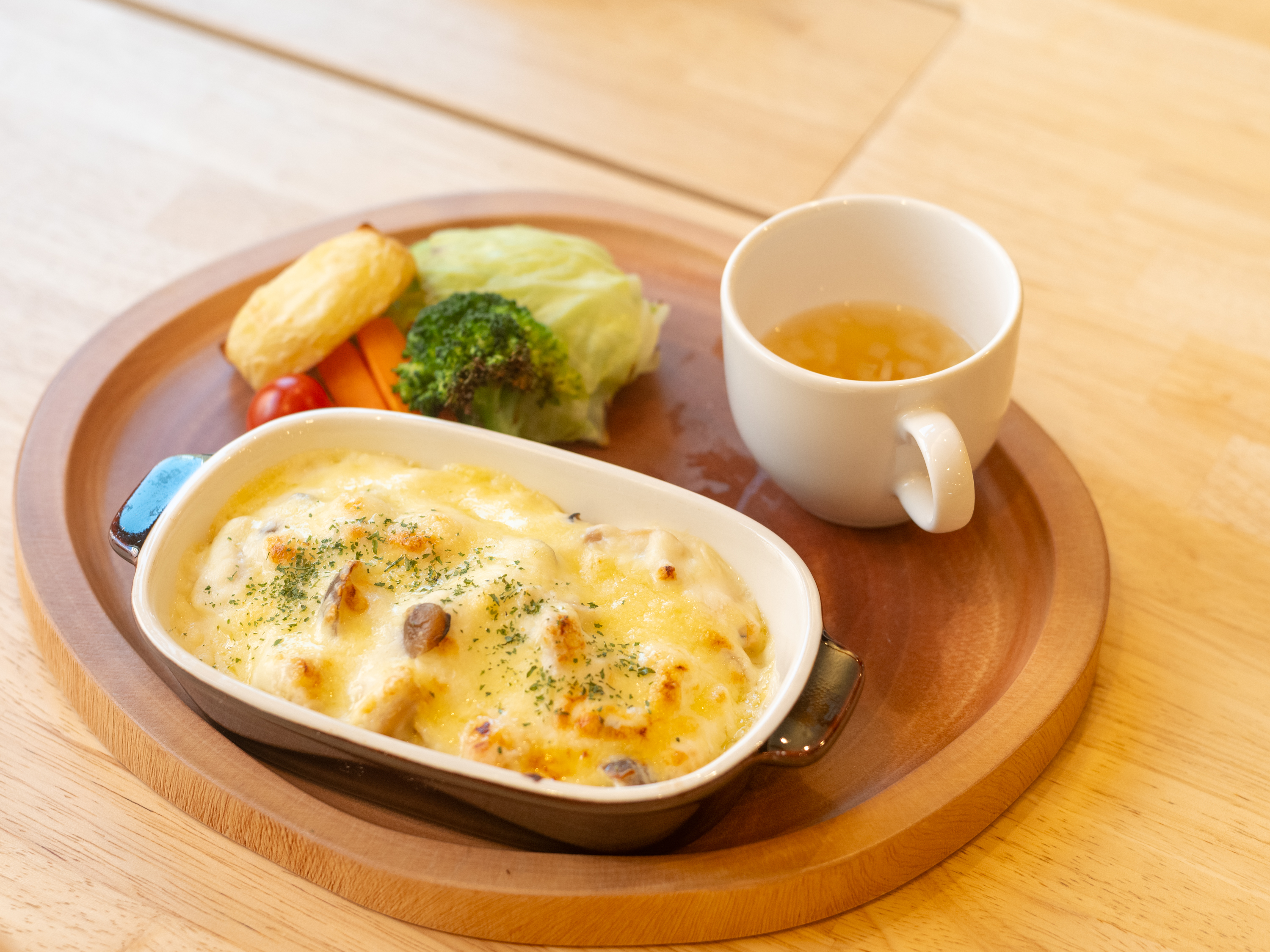 【写真】まるいおぼんに、ドリアとスープと野菜が置いてある