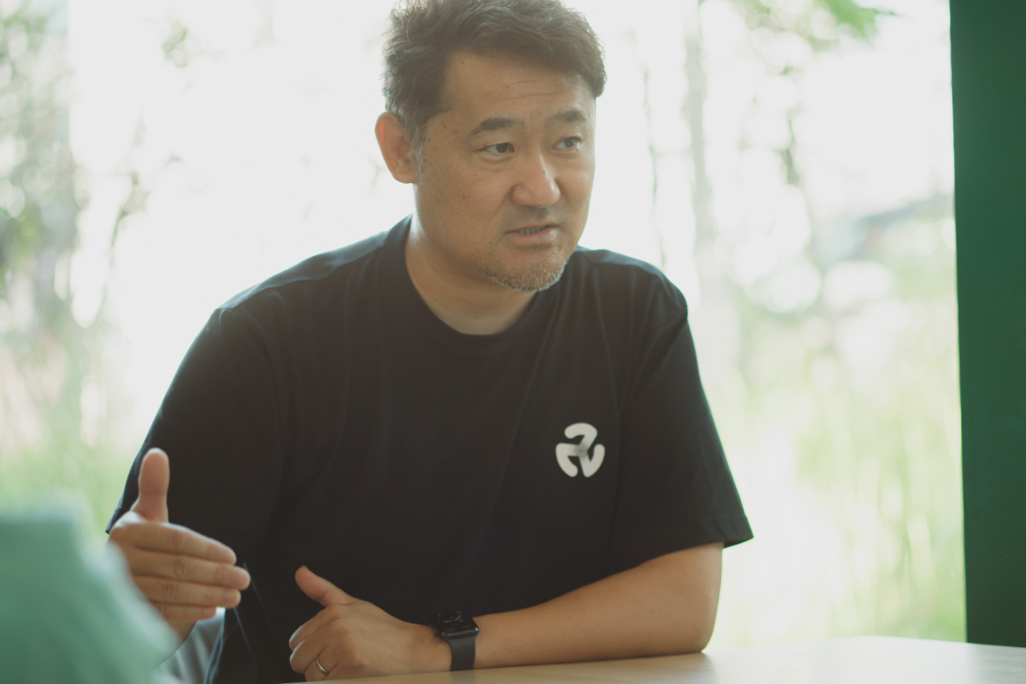 【写真】テーブルに座り真剣な表情で話す小柴さん