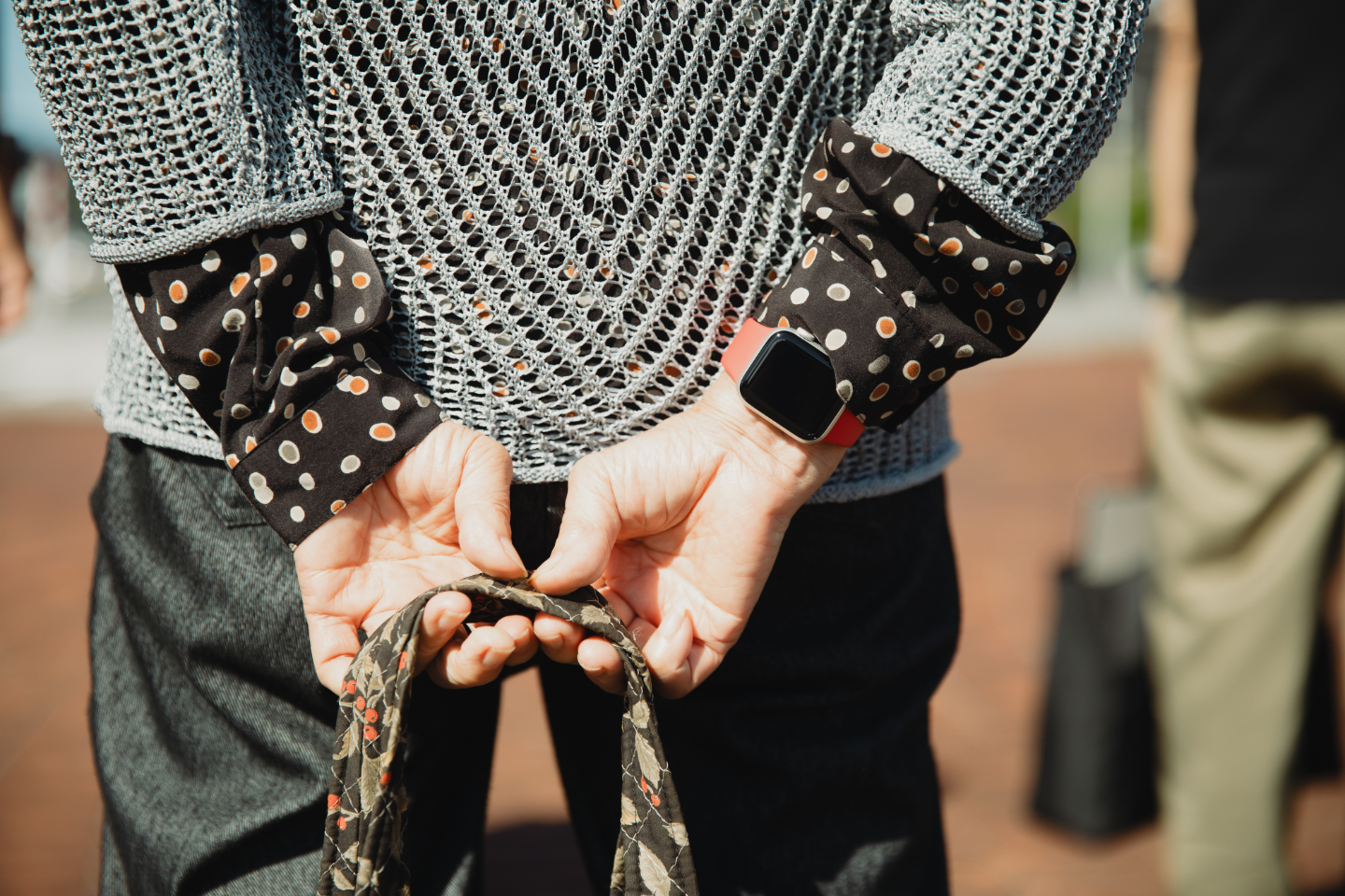 【写真】布製のかばんを両手で持って立っている参加者。腕に赤いバンドのスマートウォッチが見える