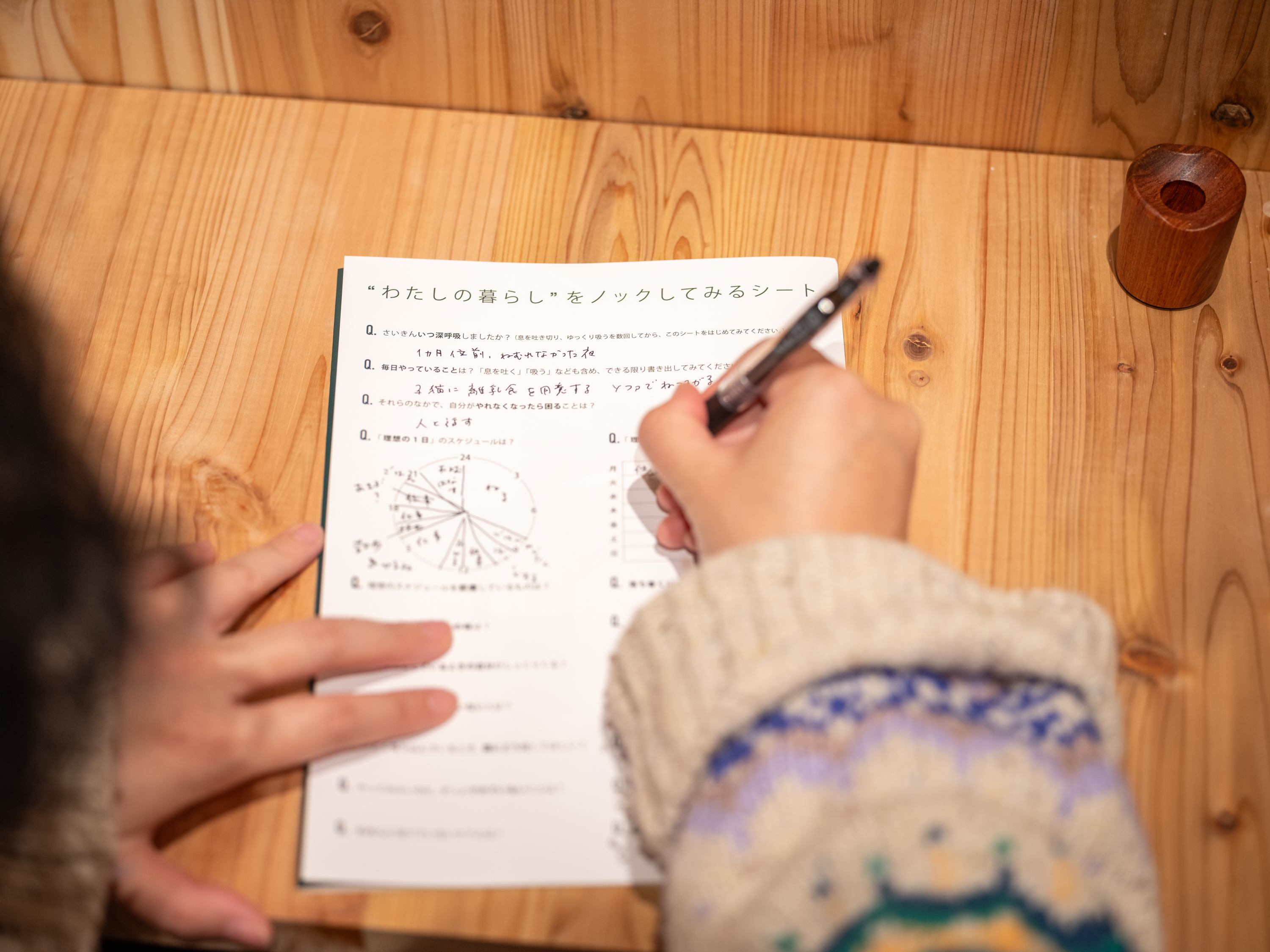 【写真】テーブルで、ノックするシートを書いている様子