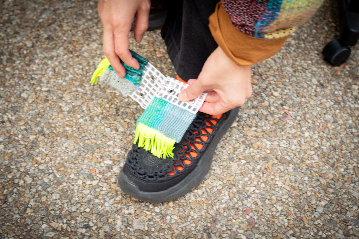 【写真】カラフルな布製のバンドを靴の甲に取り付けている様子