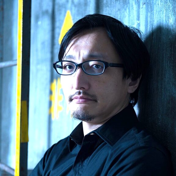 【写真】壁によりかかり、こちらを向く吉田さん