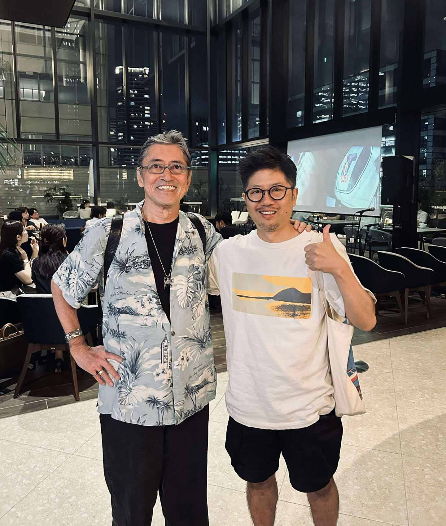 肩を組み、カメラに視線を投げるロバートさんと佐々木さんの写真。