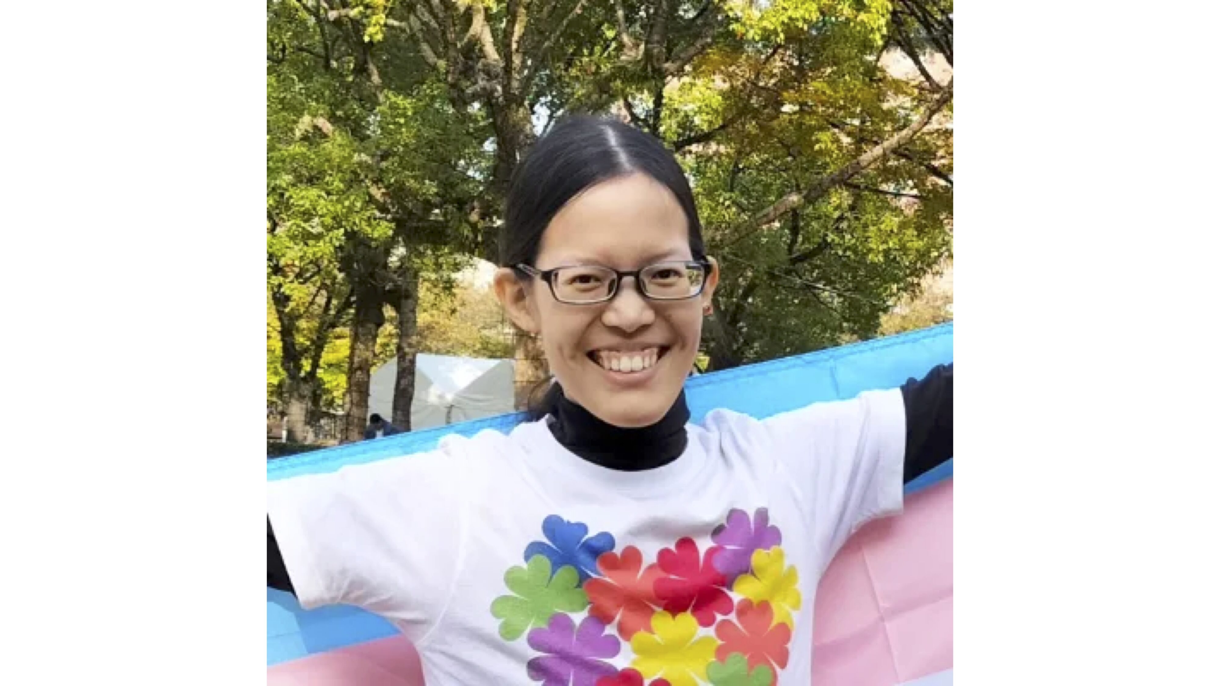 レインボーフラッグを背負ってこちらを見て微笑んでいる中島さん