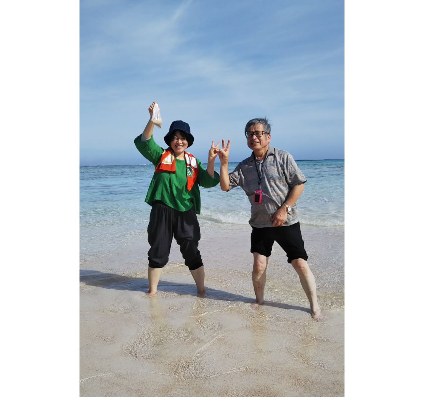 ２人が足首まで海に入り、ピースサインをしている写真