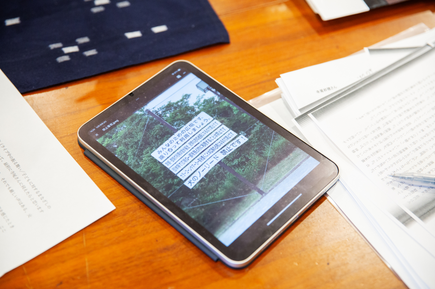 【写真】テーブルの上のタブレットに表示された、公園の看板の写真。日本語の文章で、禁止です、の文言がいくつも並ぶ