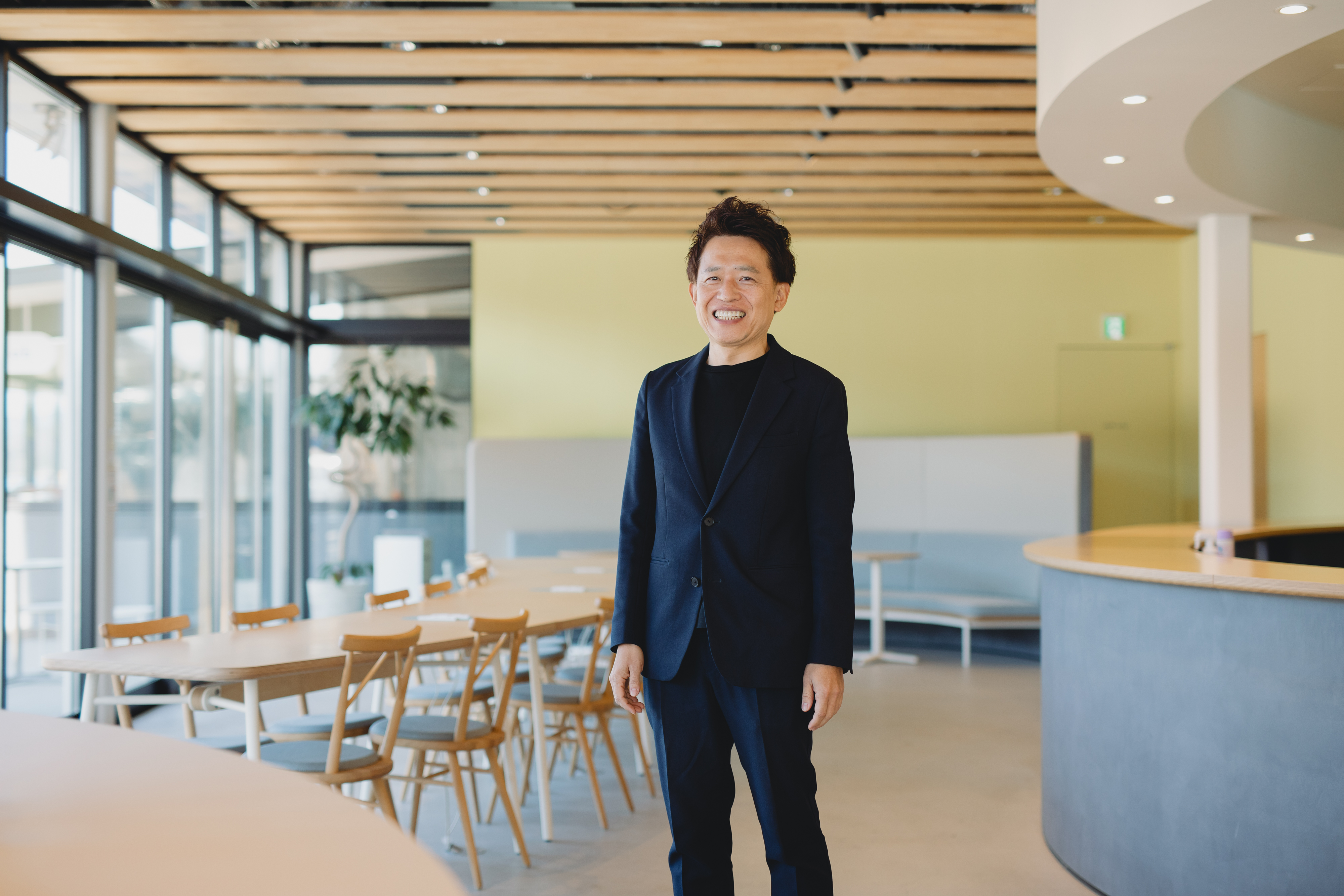 【写真】ジャケット姿でインタビューに答えるやまなかさん