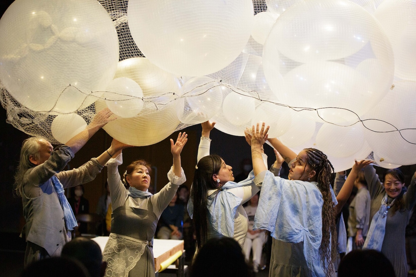 頭の上にある、白いボールを触りながら歩く人たちのシーン