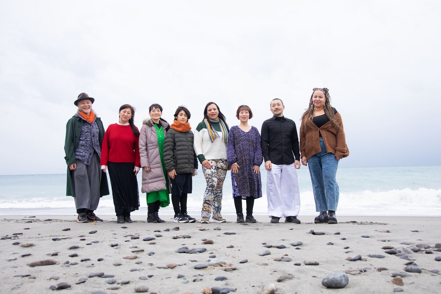 海を背景に、出演者が横一列に並んでいる