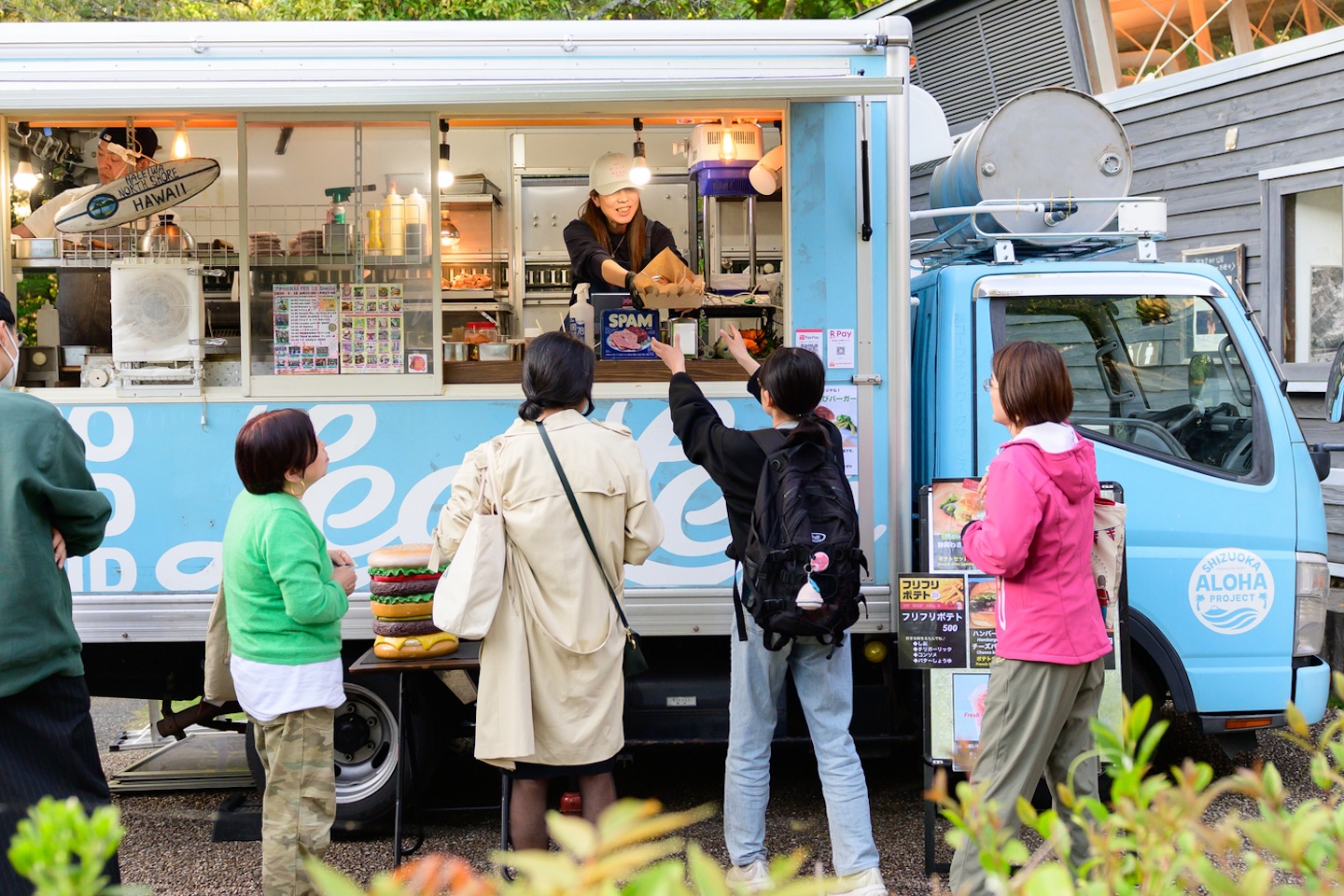 キッチンカーの前で料理を受け取る人や並ぶ人がいる様子
