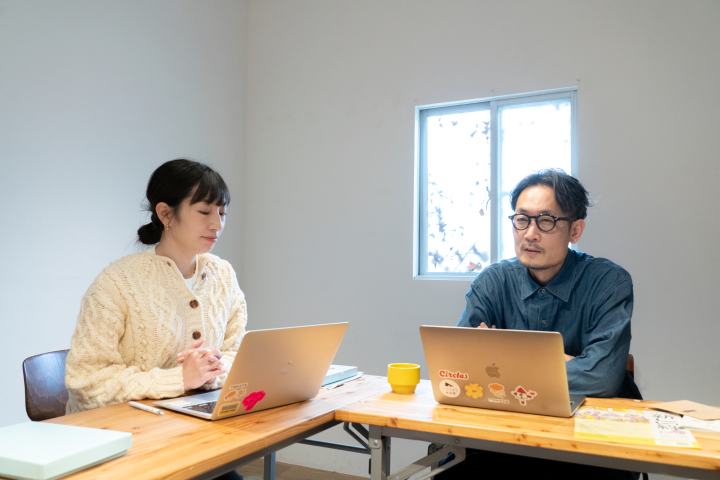 【写真】ノートパソコンを前に2人がテーブルで横向きに座っている