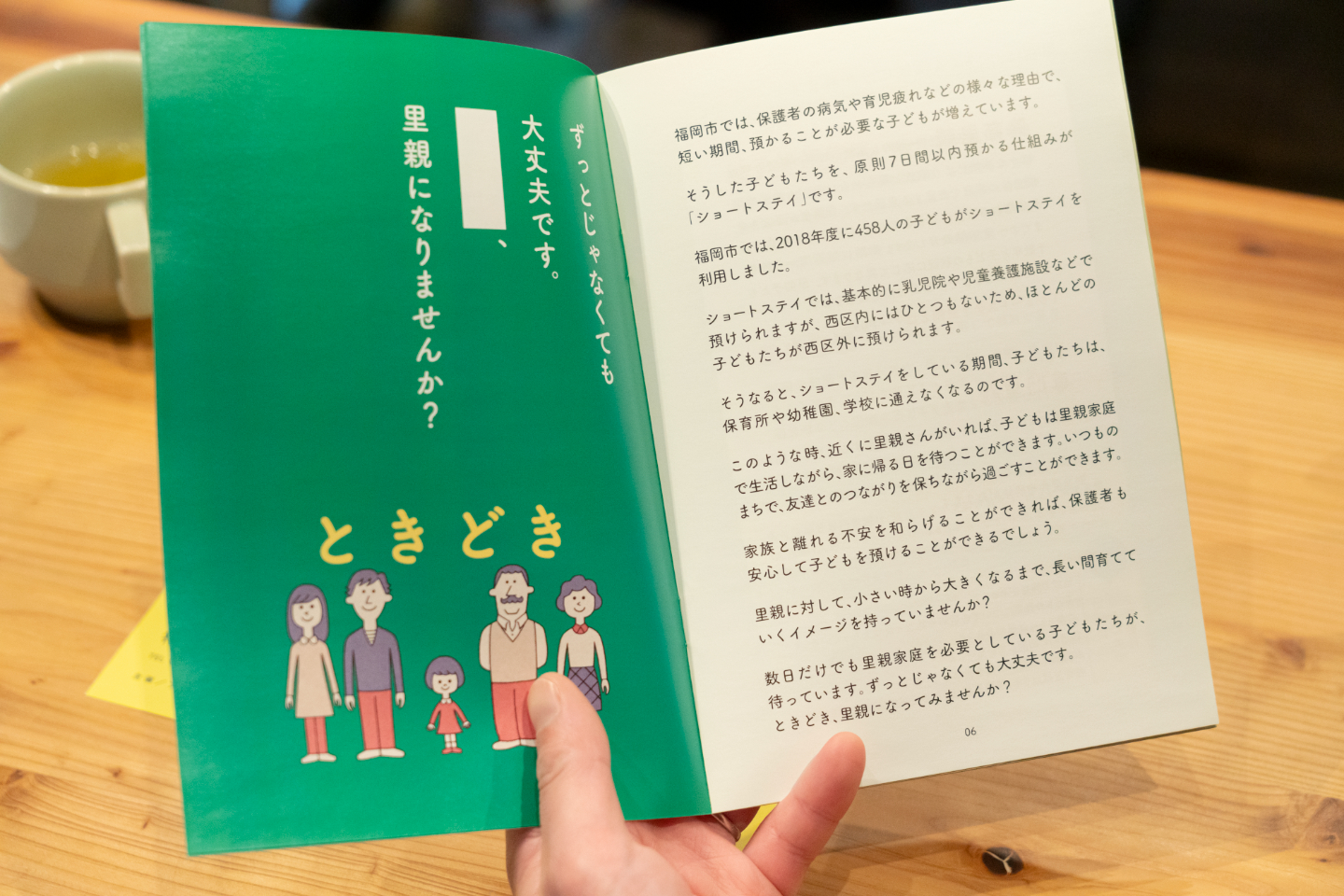 【写真】緑色のページに「里親になりませんか？、ときどき」と書かれイラストの家族が描かれている
