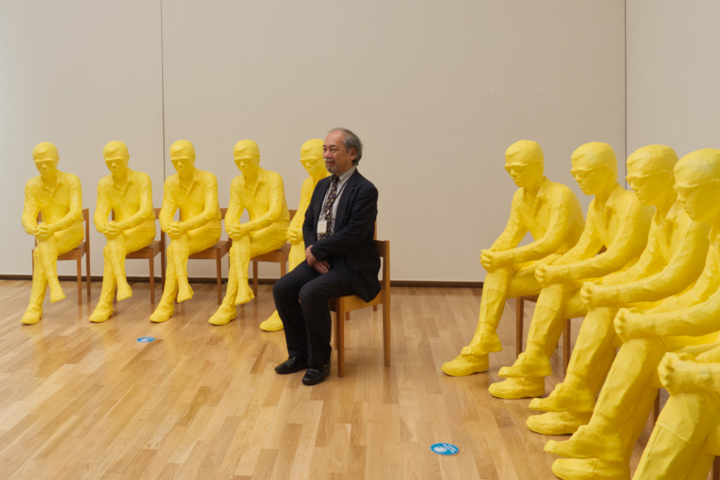 【写真】黄色い人物がたくさんいる造形の中央に、人が座っている