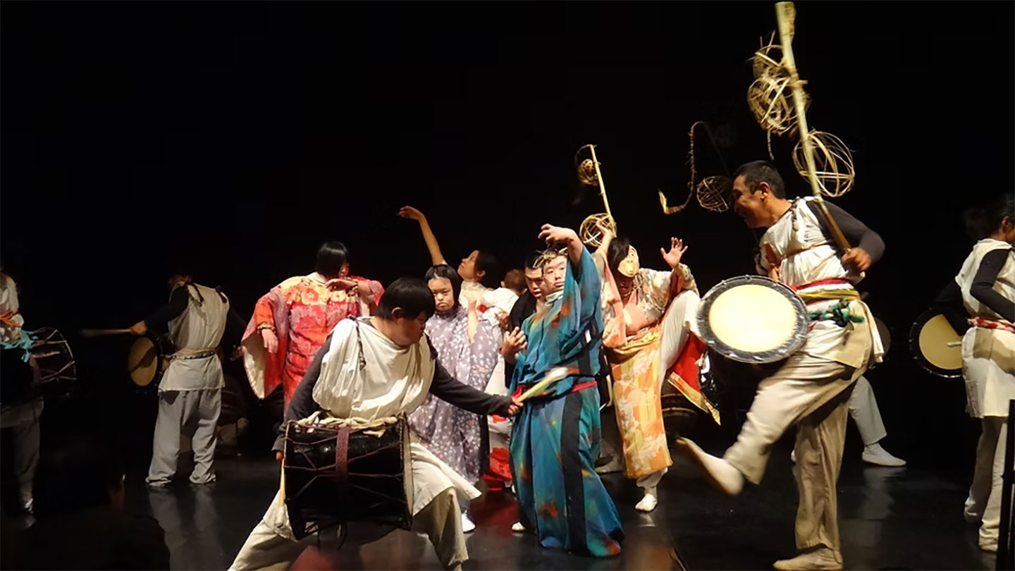 さまざまな装束衣装に身を包んだ自然生クラブのメンバーたちがステージで踊る様子。