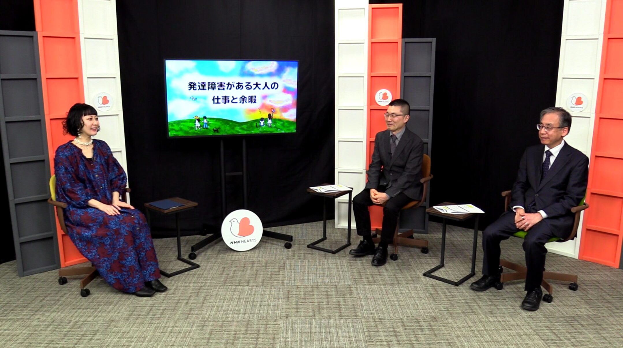 【写真】スタジオで、大きなモニター横に3人の人が座っている