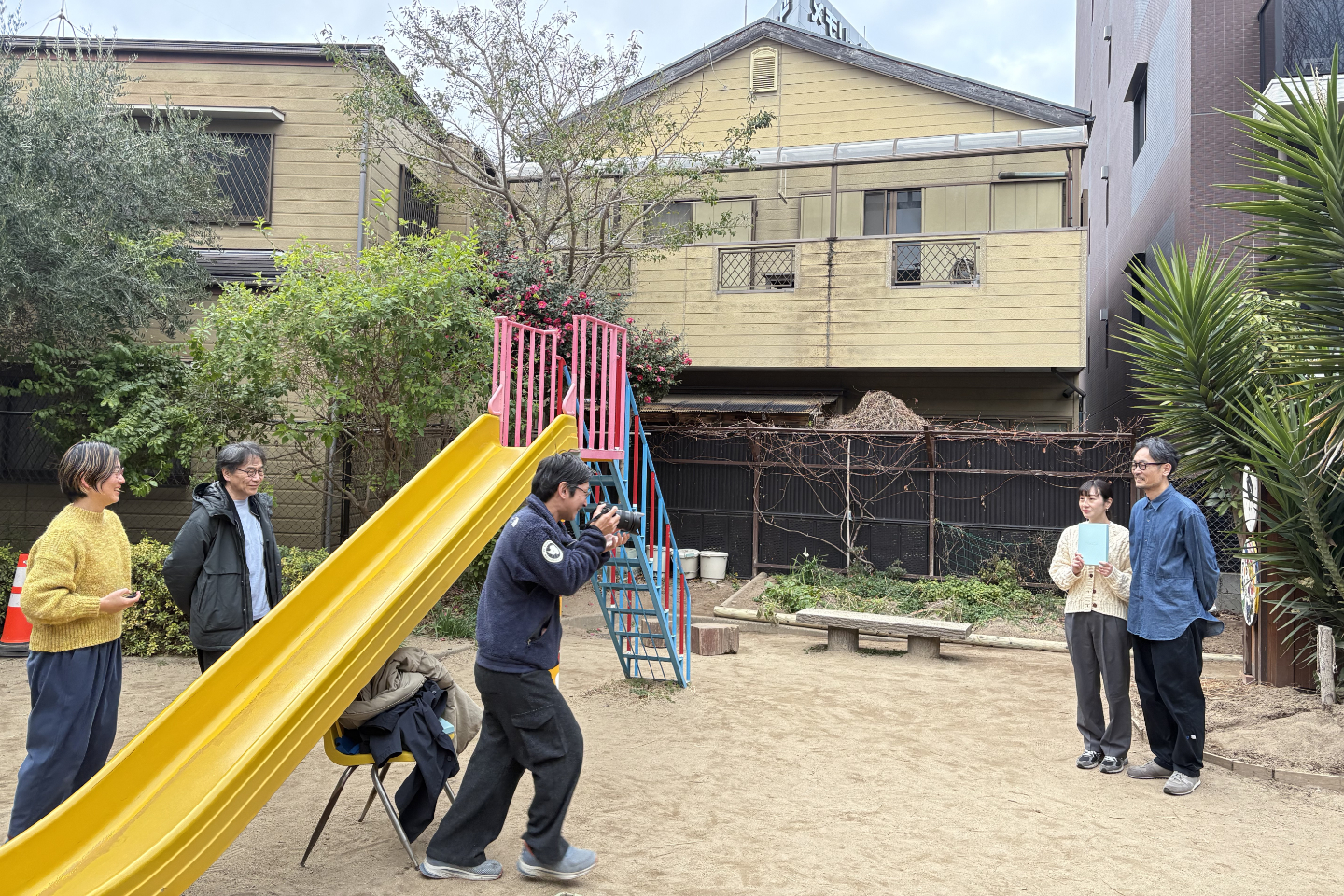 【写真】撮影中の風景。すべり台の左に酒井さん、矢島さん。カメラを構える齋藤さんを挟んで、新開さんと田北さん