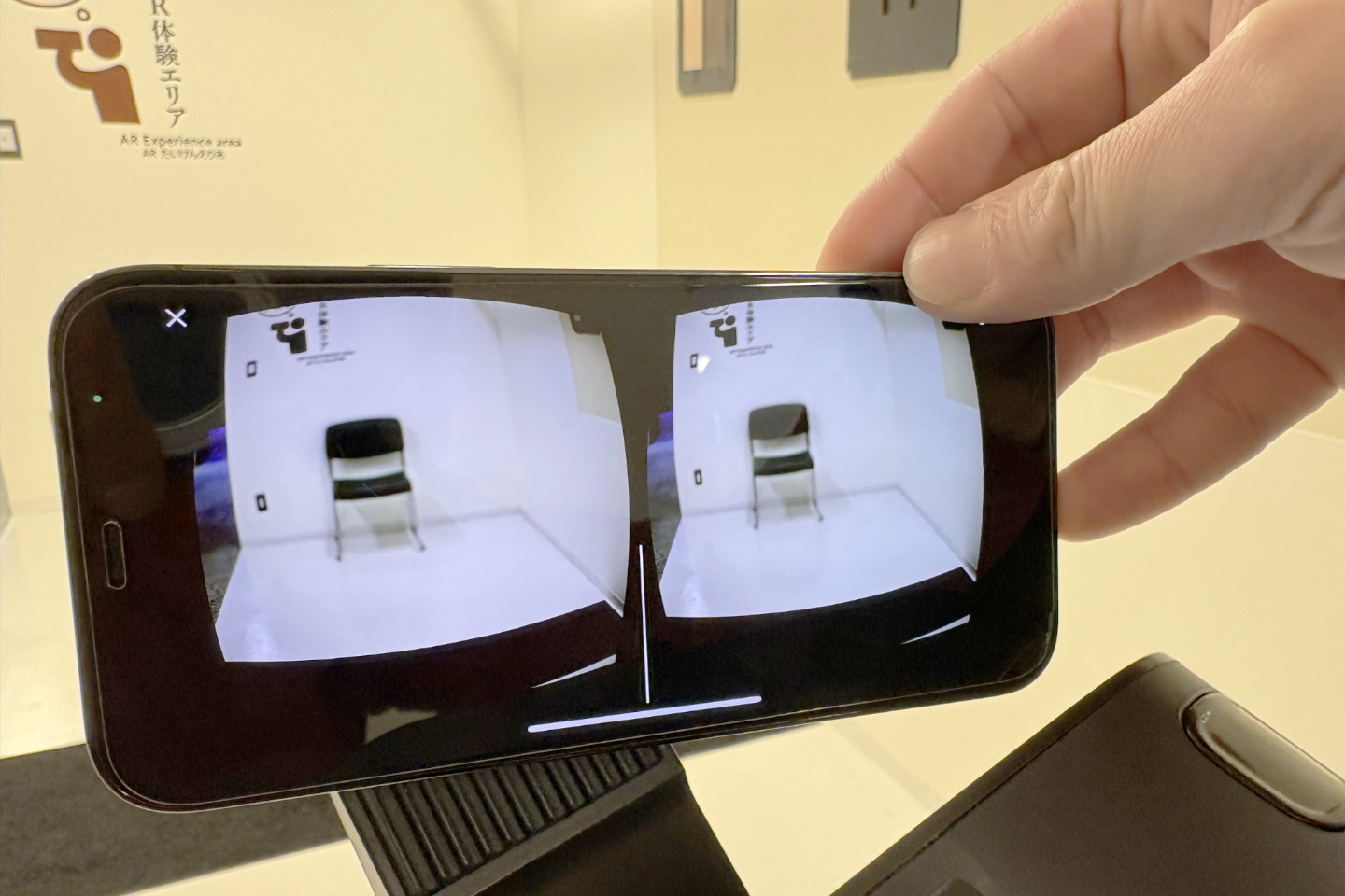 【写真】横向きのスマートフォン。ゴーグルをかけたときのような、左右2つの視点が写っているが、実際には赤い壁のイラストが黒く表示されている