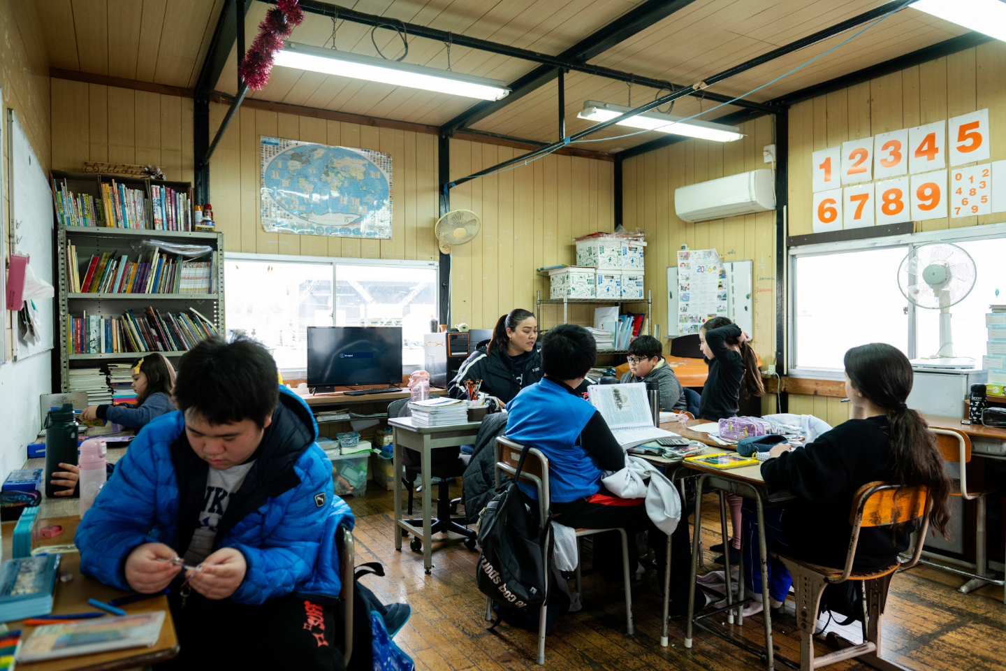 【写真】教室で、子どもたちが机を囲みながら学習している