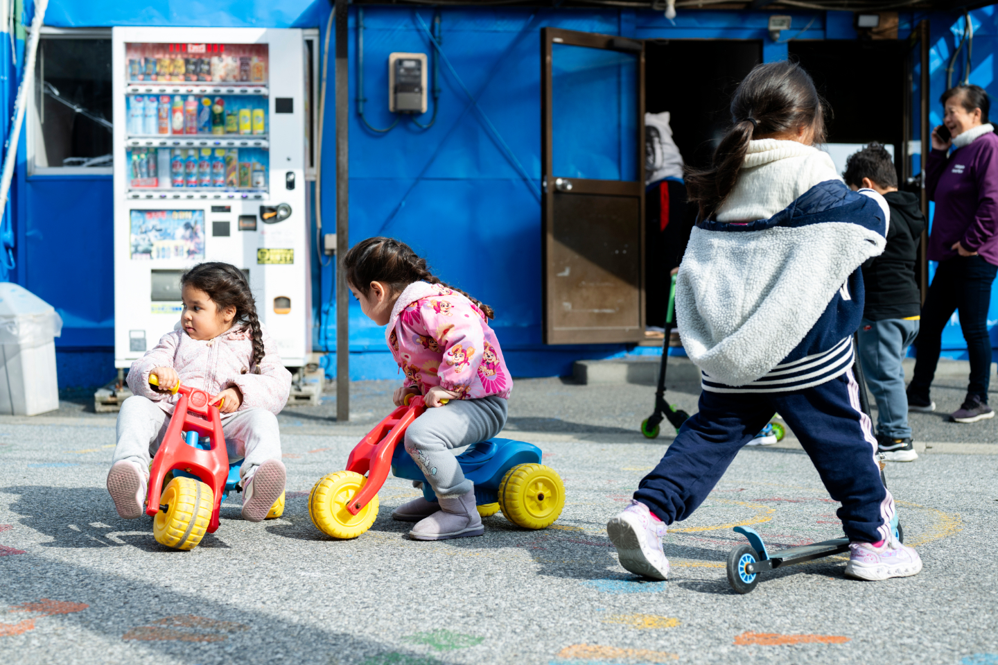 【写真】路上で幼い子どもたちが三輪車やキックボードで遊んでいる